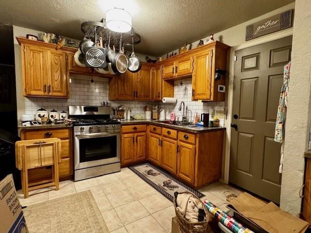 13501 E Memorial Rd, Jones, OK 73049 - kitchen with stainless steel gas range, a textured ceiling, brown cabinetry, decorative backsplash, and dark countertops