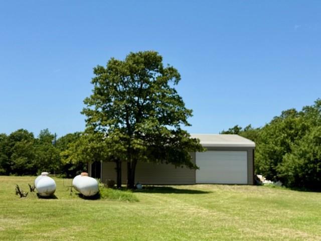 13501 E Memorial Rd, Jones, OK 73049 - view of grassy yard with driveway, a garage, and an outbuilding