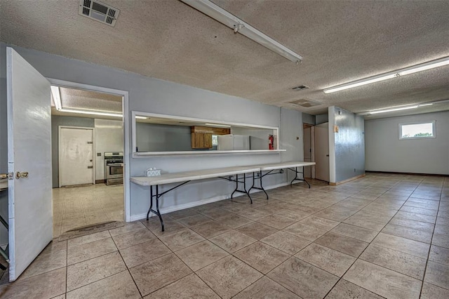 1028 N 11th St, Chickasha, OK 73018 - kitchen with tile patterned flooring, a textured ceiling, wall oven, and a breakfast bar