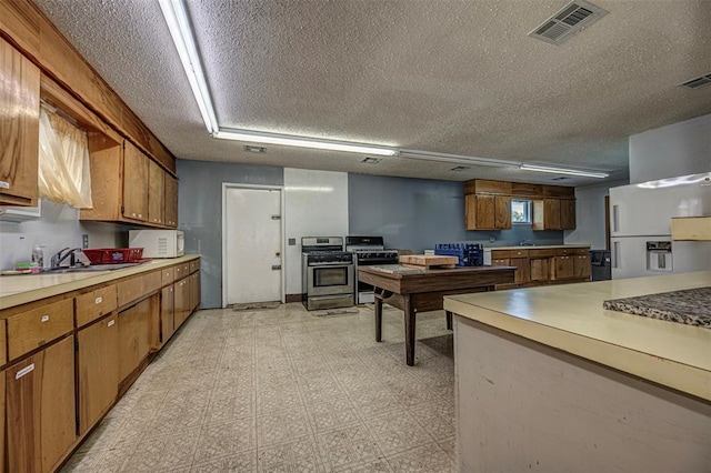 1028 N 11th St, Chickasha, OK 73018 - kitchen with white appliances, brown cabinetry, light countertops, a textured ceiling, and light floors