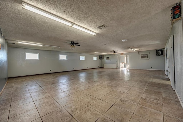 1028 N 11th St, Chickasha, OK 73018 - empty room featuring ceiling fan, light tile patterned floors, a textured ceiling, and a wall unit AC