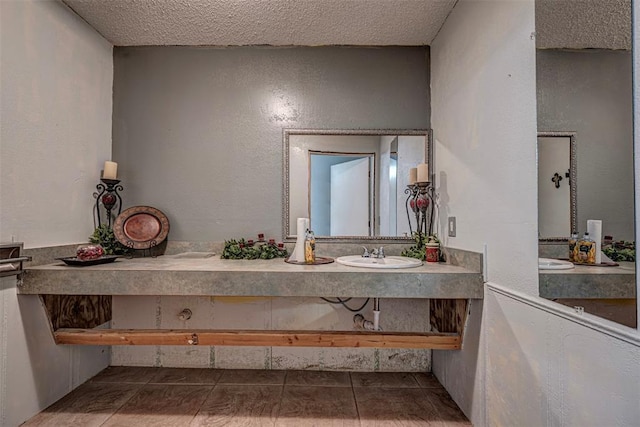 1028 N 11th St, Chickasha, OK 73018 - bathroom with a textured ceiling, double vanity, tile patterned floors, and a textured wall