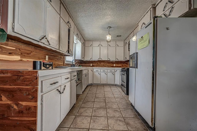 1028 N 11th St, Chickasha, OK 73018 - kitchen featuring freestanding refrigerator, white cabinetry, gas stove, a textured ceiling, and light countertops