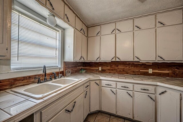 1028 N 11th St, Chickasha, OK 73018 - kitchen featuring tile countertops, white cabinets, and a textured ceiling