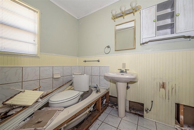 1028 N 11th St, Chickasha, OK 73018 - bathroom featuring crown molding, a bathtub, and a wainscoted wall