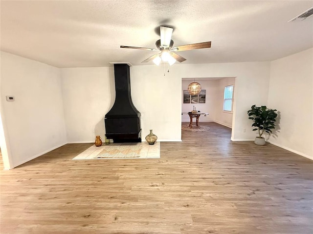 1402 S 14th St, Chickasha, OK 73018 - living area with wood finished floors, a wood stove, a ceiling fan, and a textured ceiling