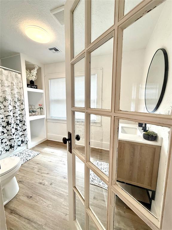 1402 S 14th St, Chickasha, OK 73018 - bathroom featuring wood finished floors, vanity, a textured ceiling, and a shower with shower curtain