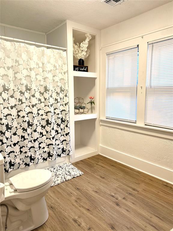 1402 S 14th St, Chickasha, OK 73018 - bathroom with wood finished floors and curtained shower