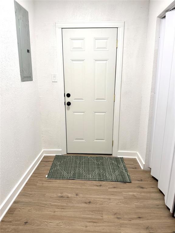 1402 S 14th St, Chickasha, OK 73018 - doorway to outside with electric panel and wood finished floors