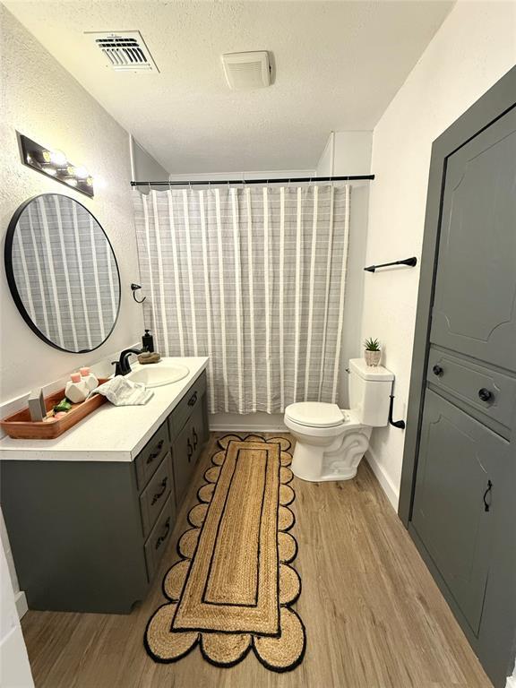 1402 S 14th St, Chickasha, OK 73018 - bathroom with wood finished floors, vanity, and a textured ceiling