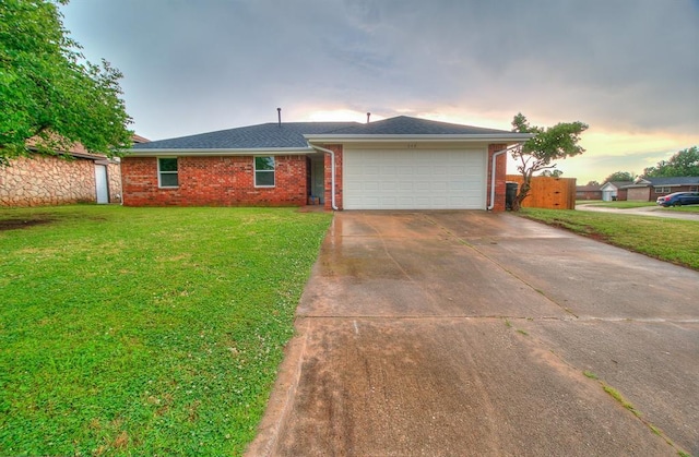 648 NW 18th St, Moore, OK 73160 - ranch-style house with brick siding, an attached garage, driveway, and a lawn