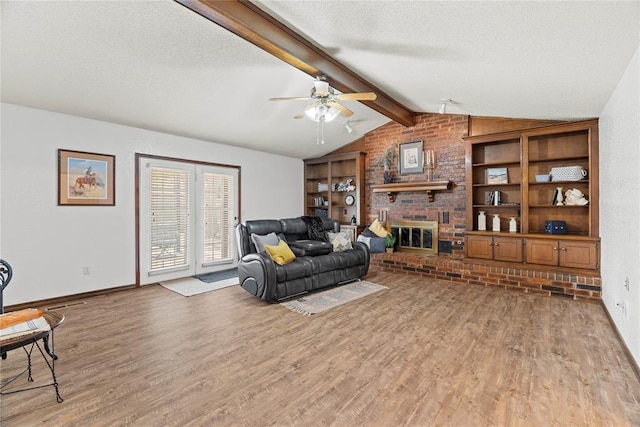 1912 Magnolia Ln, Edmond, OK 73013 - living room featuring light wood finished floors, a ceiling fan, a textured ceiling, a fireplace, and built in shelves