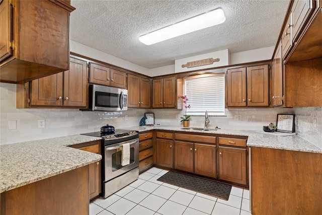 1912 Magnolia Ln, Edmond, OK 73013 - kitchen featuring stainless steel appliances, a textured ceiling, backsplash, and brown cabinetry