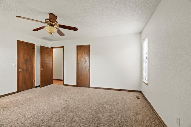 1912 Magnolia Ln, Edmond, OK 73013 - unfurnished bedroom featuring light carpet, a textured ceiling, ceiling fan, a textured wall, and two closets