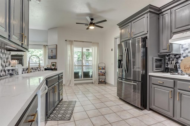 613 N Remington Way, Mustang, OK 73064 - kitchen featuring stainless steel appliances, gray cabinetry, ceiling fan, light tile patterned flooring, and under cabinet range hood