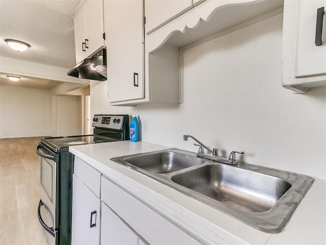 2924 SW 51st St, Oklahoma City, OK 73119 - kitchen with stainless steel electric range, under cabinet range hood, light countertops, light wood-style floors, and white cabinets