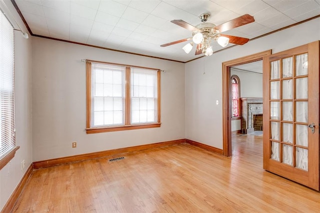 2705 NW 21st St, Oklahoma City, OK 73107 - unfurnished room with light wood-type flooring, crown molding, a brick fireplace, and ceiling fan