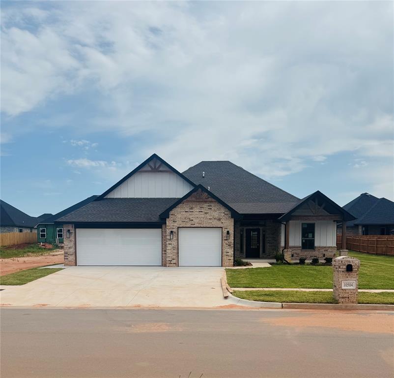 10504 SW 50th St, Mustang, OK 73064 - view of front of house featuring board and batten siding, an attached garage, driveway, and brick siding