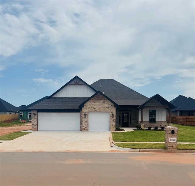 10504 SW 50th St, Mustang, OK 73064 - view of front of house featuring board and batten siding, an attached garage, driveway, and brick siding