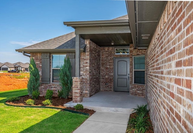 2001 W Crossbow Way, Mustang, OK 73065 - doorway to property with brick siding, roof with shingles, and a yard