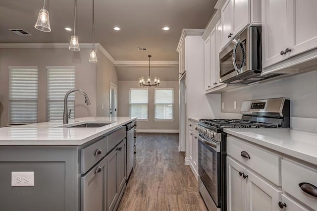 2001 W Crossbow Way, Mustang, OK 73065 - kitchen featuring stainless steel appliances, gray cabinets, ornamental molding, light countertops, and a center island with sink