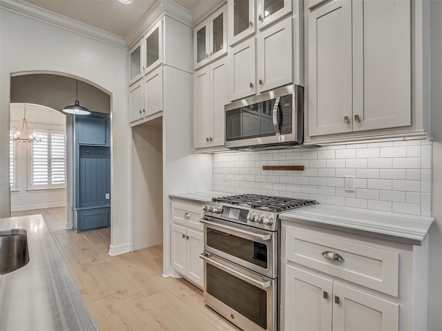 8408 NW 134th St, Oklahoma City, OK 73142 - kitchen with appliances with stainless steel finishes, light countertops, ornamental molding, light wood finished floors, and decorative backsplash