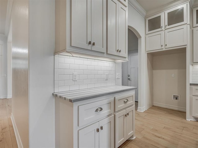 8408 NW 134th St, Oklahoma City, OK 73142 - kitchen with arched walkways, decorative backsplash, light wood-style flooring, glass insert cabinets, and light countertops