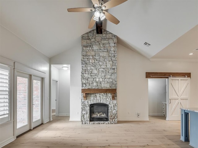 8408 NW 134th St, Oklahoma City, OK 73142 - unfurnished living room featuring a ceiling fan, light wood-style flooring, a fireplace, a barn door, and high vaulted ceiling