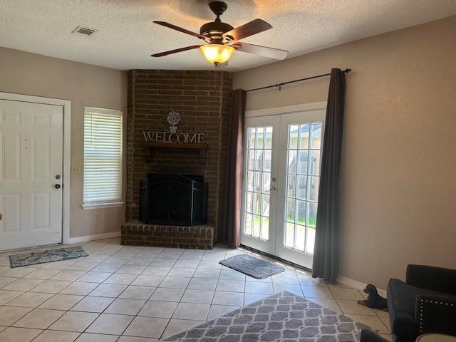 1208 SW 21st St, Oklahoma City, OK 73170 - living room featuring light tile patterned floors, french doors, a textured ceiling, ceiling fan, and a fireplace
