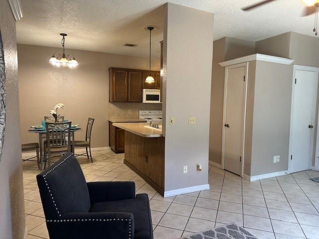 1208 SW 21st St, Oklahoma City, OK 73170 - kitchen with white microwave, light tile patterned floors, a textured ceiling, ceiling fan, and light countertops