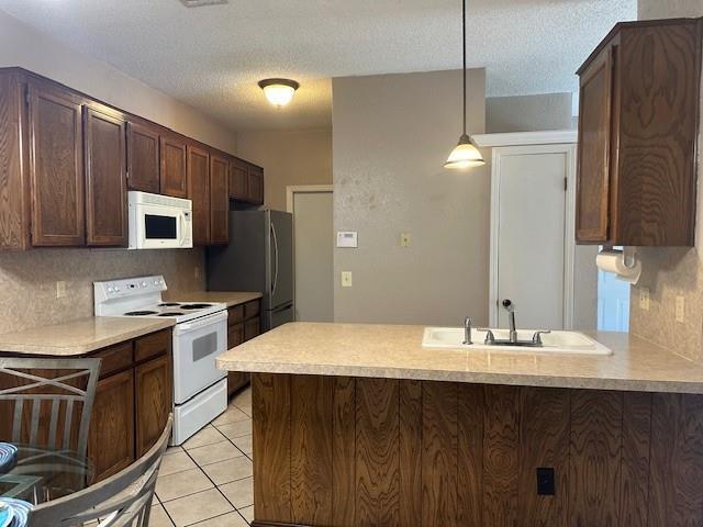 1208 SW 21st St, Oklahoma City, OK 73170 - kitchen featuring white appliances, a peninsula, light countertops, dark brown cabinets, and light tile patterned flooring