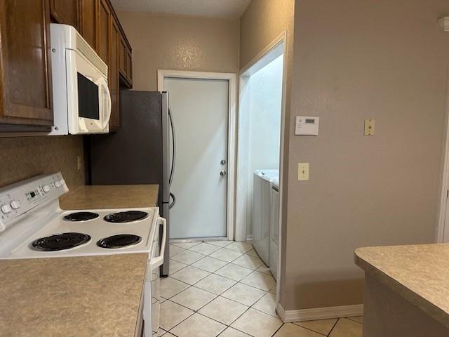 1208 SW 21st St, Oklahoma City, OK 73170 - kitchen featuring white appliances, light tile patterned flooring, light countertops, and washer / dryer