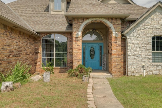 4120 S Choctaw Rd, Choctaw, OK 73020 - view of exterior entry featuring a shingled roof, brick siding, a yard, and stone siding