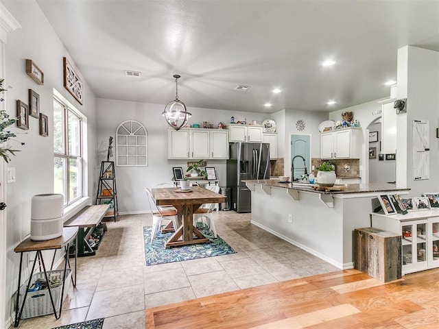 21945 N Fork Rd, Luther, OK 73054 - kitchen featuring stainless steel refrigerator with ice dispenser, a breakfast bar area, a chandelier, tasteful backsplash, and recessed lighting