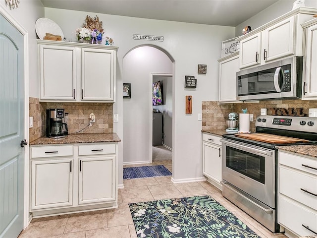 21945 N Fork Rd, Luther, OK 73054 - kitchen with appliances with stainless steel finishes, arched walkways, decorative backsplash, light stone counters, and light tile patterned floors
