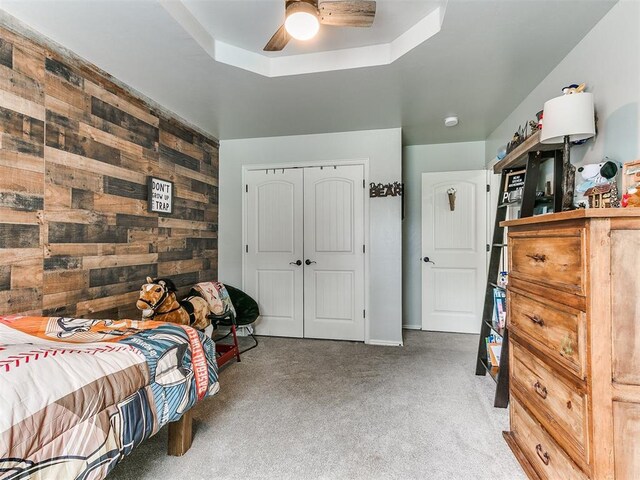 21945 N Fork Rd, Luther, OK 73054 - bedroom with carpet floors, wooden walls, a closet, ceiling fan, and a tray ceiling