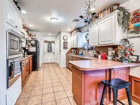 23 Lake Ln, Shawnee, OK 74804 - kitchen with stainless steel appliances, a peninsula, light tile patterned flooring, white cabinets, and recessed lighting