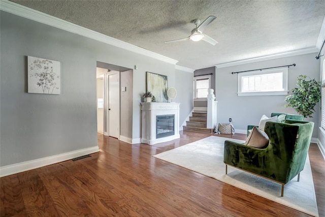 904 NW 19th St, Oklahoma City, OK 73106 - living area with crown molding, a textured ceiling, ceiling fan, a glass covered fireplace, and wood finished floors