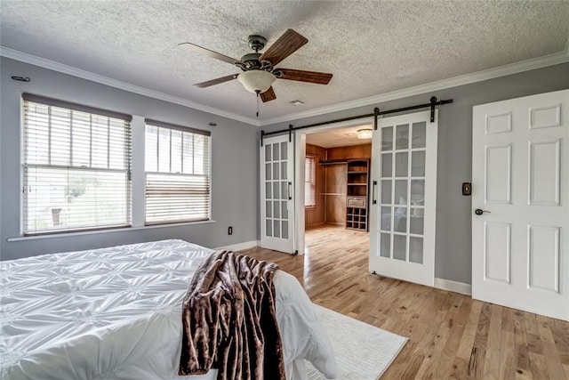 904 NW 19th St, Oklahoma City, OK 73106 - bedroom with a barn door, light wood-type flooring, crown molding, a textured ceiling, and ceiling fan