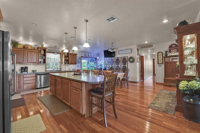 22071 E 1250th Rd, Rocky, OK 73661 - kitchen with appliances with stainless steel finishes, open shelves, light wood-type flooring, a kitchen breakfast bar, and a center island