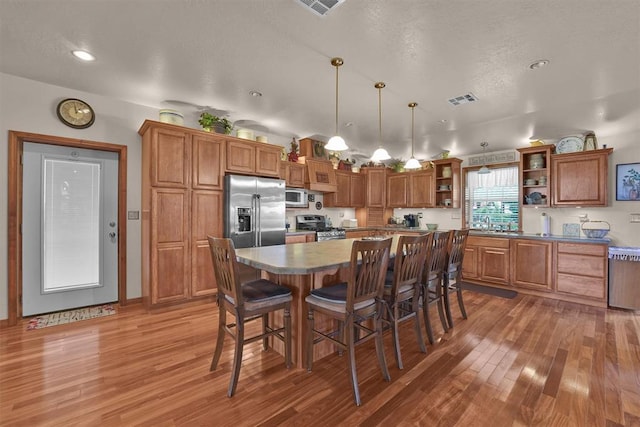 22071 E 1250th Rd, Rocky, OK 73661 - kitchen featuring open shelves, light wood-style floors, stainless steel appliances, a kitchen bar, and recessed lighting