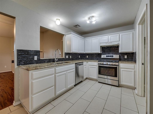 12300 NW 4th St, Yukon, OK 73099 - kitchen featuring stainless steel appliances, backsplash, under cabinet range hood, white cabinets, and light stone counters