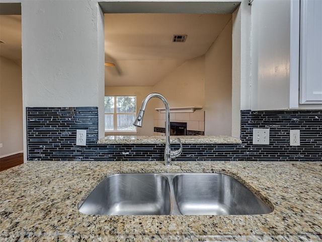 12300 NW 4th St, Yukon, OK 73099 - kitchen view of decorative backsplash, light stone counters, white cabinets, and a ceiling fan