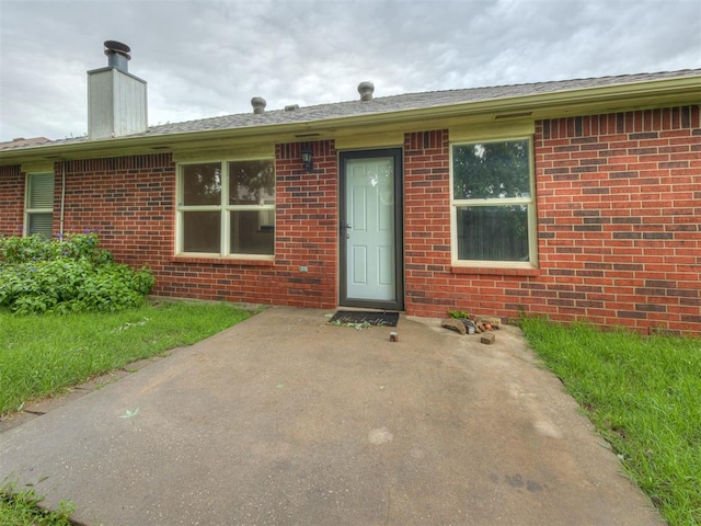 12300 NW 4th St, Yukon, OK 73099 - view of front facade featuring brick siding, a patio, and a chimney