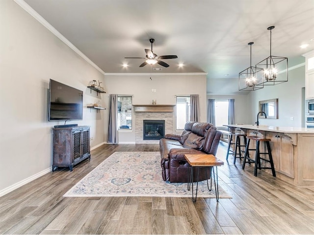8401 Poplar Dr, Edmond, OK 73034 - living area featuring a stone fireplace, light wood-style flooring, ceiling fan, crown molding, and recessed lighting