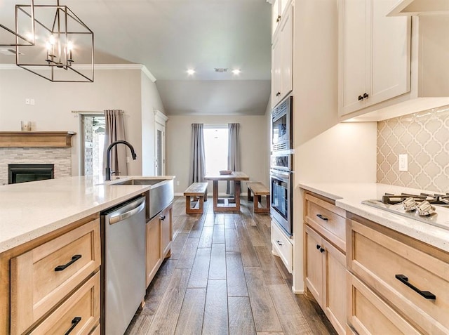 8401 Poplar Dr, Edmond, OK 73034 - kitchen featuring appliances with stainless steel finishes, a glass covered fireplace, light brown cabinetry, dark wood finished floors, and recessed lighting