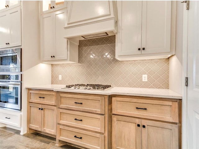 8401 Poplar Dr, Edmond, OK 73034 - kitchen featuring appliances with stainless steel finishes, premium range hood, decorative backsplash, glass insert cabinets, and light brown cabinetry