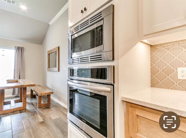 8401 Poplar Dr, Edmond, OK 73034 - kitchen with appliances with stainless steel finishes, light stone countertops, light wood-type flooring, lofted ceiling, and white cabinets