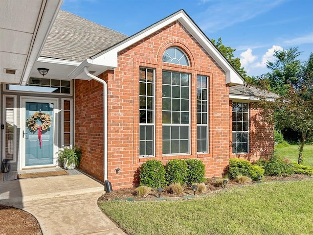 12200 Whispering Pnes, Guthrie, OK 73044 - doorway to property featuring brick siding, roof with shingles, and a lawn