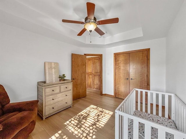 12200 Whispering Pnes, Guthrie, OK 73044 - bedroom featuring a tray ceiling, light wood-type flooring, a closet, and a ceiling fan
